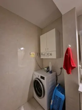 Bathroom equipped with ceramic tiles, a washing machine, and a white cabinet. - image 19