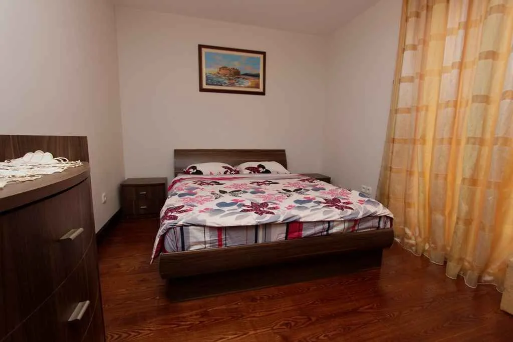 A bedroom with a double bed and wooden flooring.