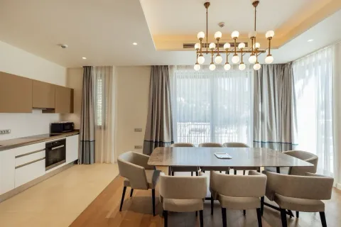 Trpezarija sa velikim stolom i modernim lusterom povezana sa kuhinjom. - image 10