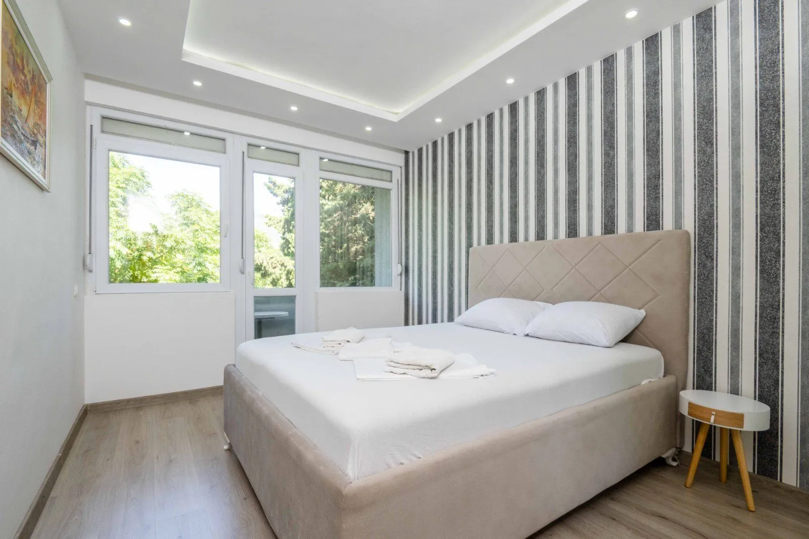 Bright bedroom with a double bed, wallpaper, and balcony access.