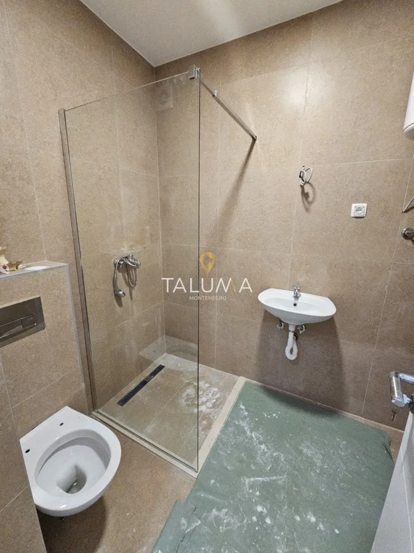 Kupatilo opremljeno tuš kabinom sa staklenim paravanom, umivaonikom i toaletom.