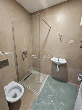 Kupatilo opremljeno tuš kabinom sa staklenim paravanom, umivaonikom i toaletom. - image 4