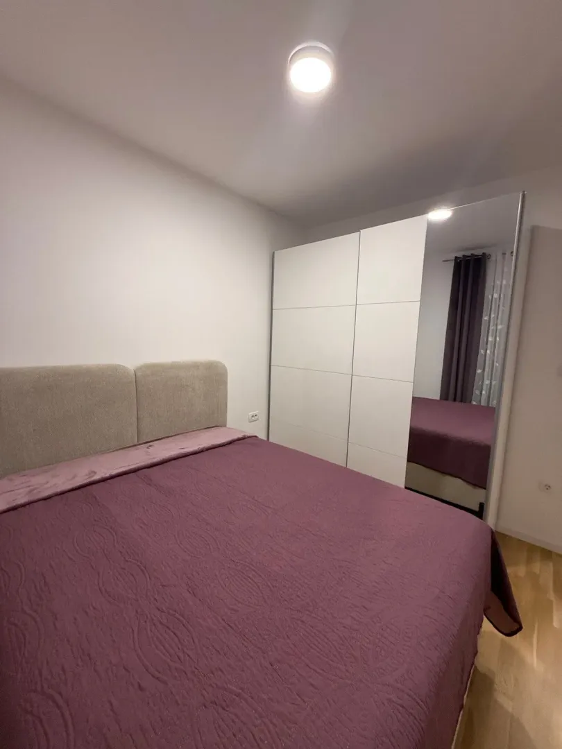 Namještena spavaća soba sa bračnim krevetom i velikim ormarom.