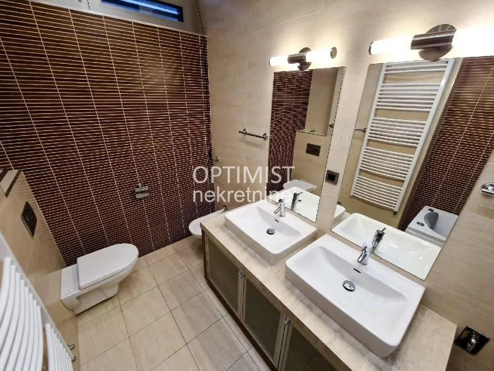 Modern bathroom equipped with two washbasins and brown wall tiles.