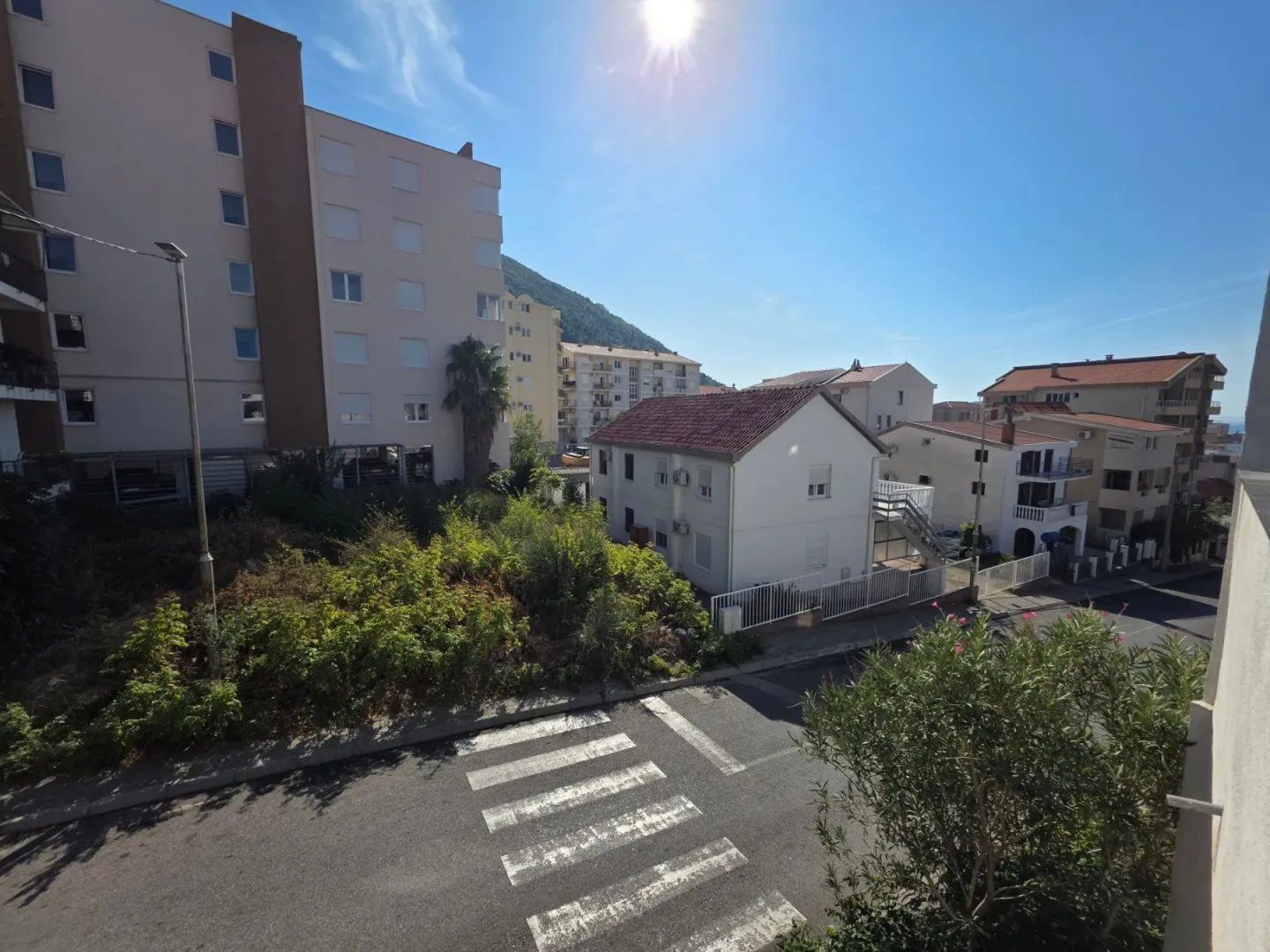 View from the window of surrounding buildings, street, and greenery.