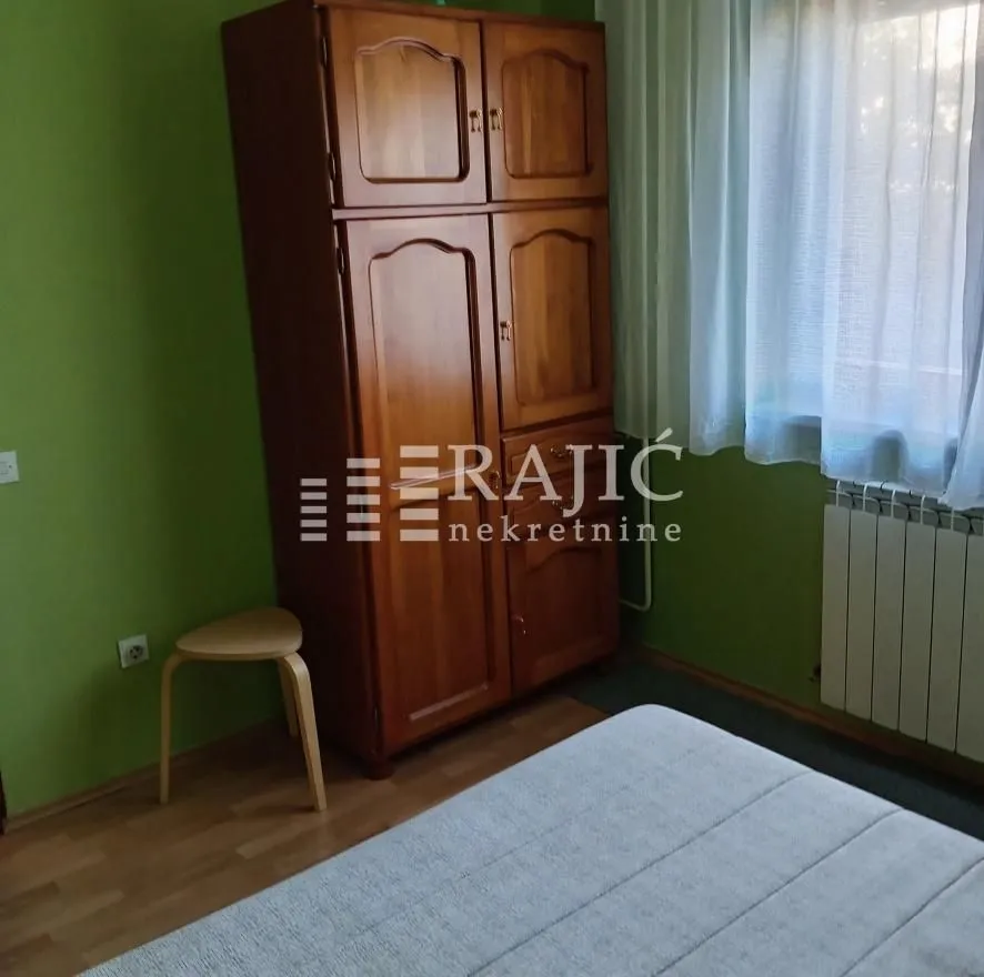 Furnished bedroom with a wooden wardrobe and a bed.