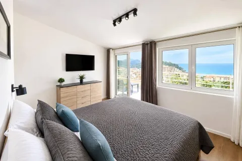 Bedroom with a double bed, dresser, TV, and a sea view. - image 7