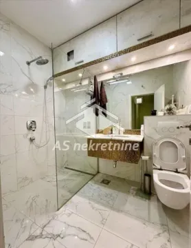 Savremeno opremljeno kupatilo sa tuš kabinom obloženom staklenom pregradom i mermernim pločicama. - image 4