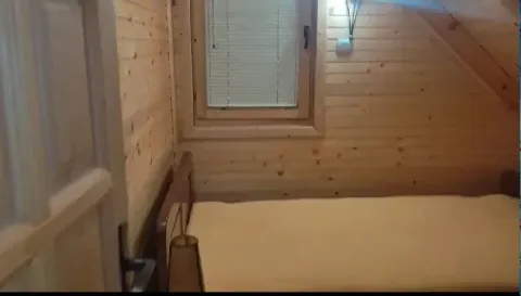 Mala spavaća soba obložena drvetom sa jednostavnim krevetom i prozorom. - image 16
