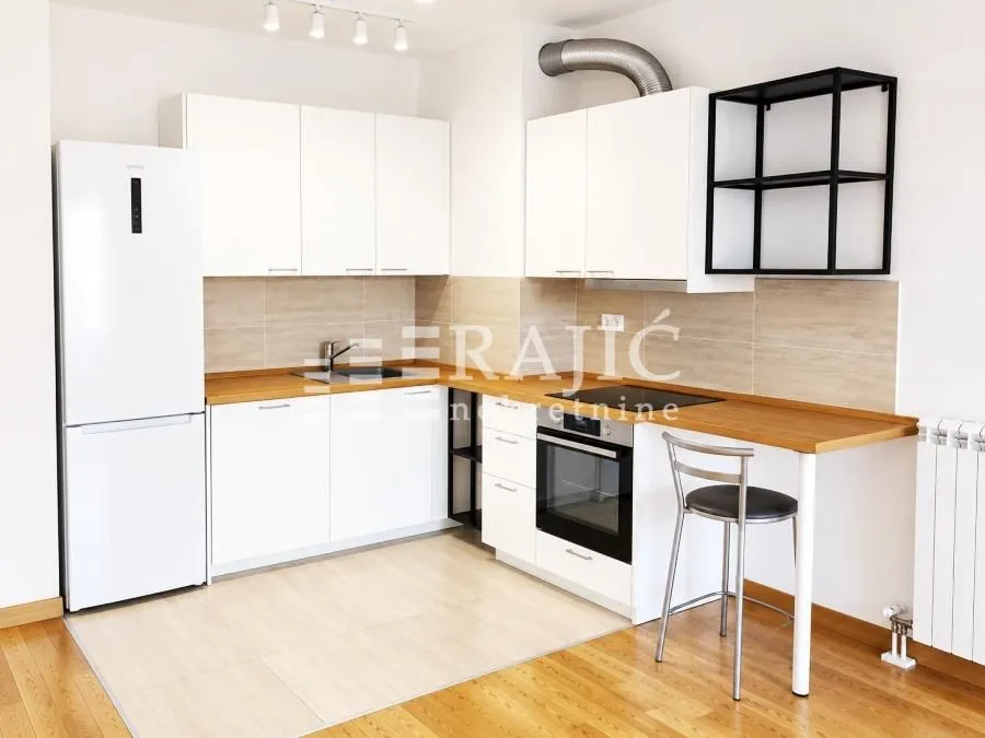 Modern white kitchen with wooden countertops and built-in appliances.