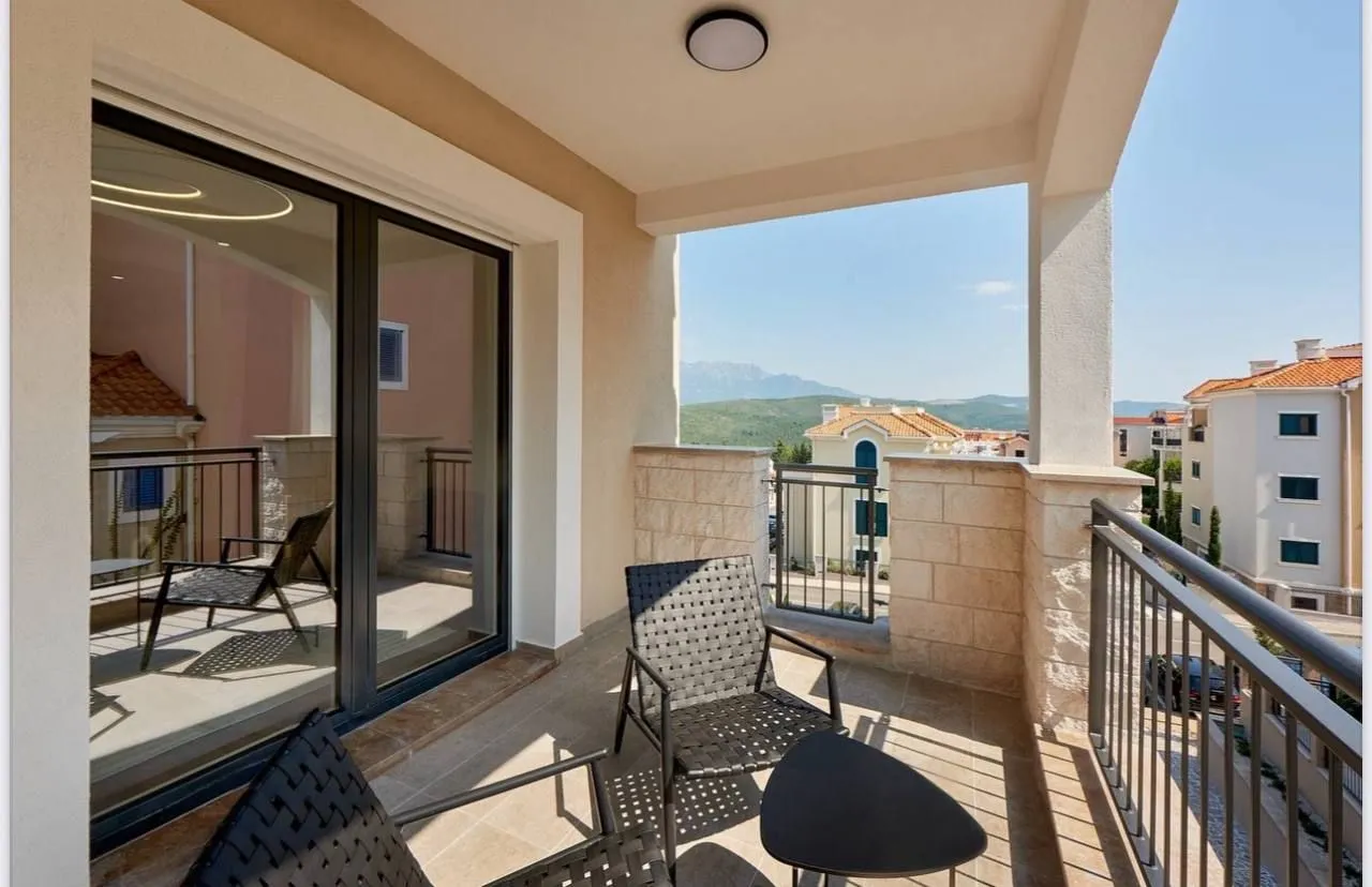 Natkrivena terasa sa garniturom za sedenje i pogledom na naselje i okolna brda.