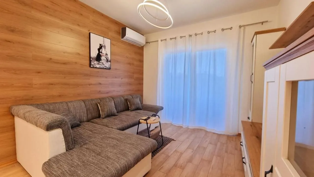 Living room with a sectional sofa, wooden wall panels, and access to the terrace.