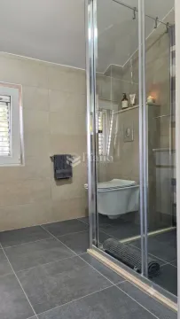Savremeno opremljeno kupatilo sa tuš kabinom i ugradnom šoljom. - image 7