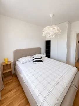 Spavaća soba sa bračnim krevetom, bijelim ormarom i drvenim podom. - image 8