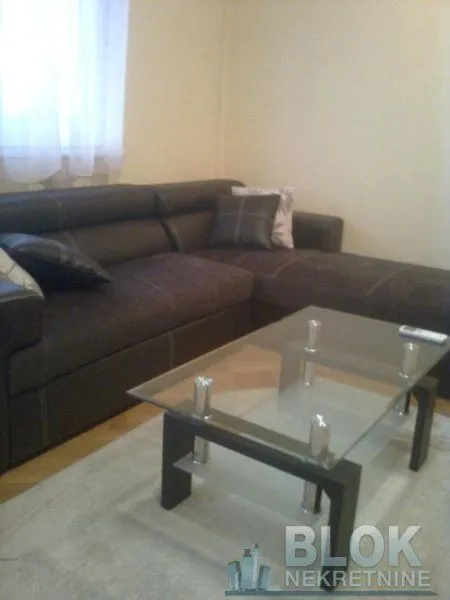 Living room with a dark sectional sofa and a glass coffee table.