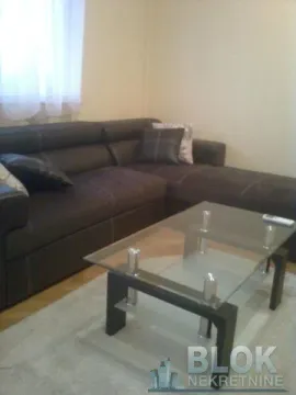 Living room with a dark sectional sofa and a glass coffee table. - image 4