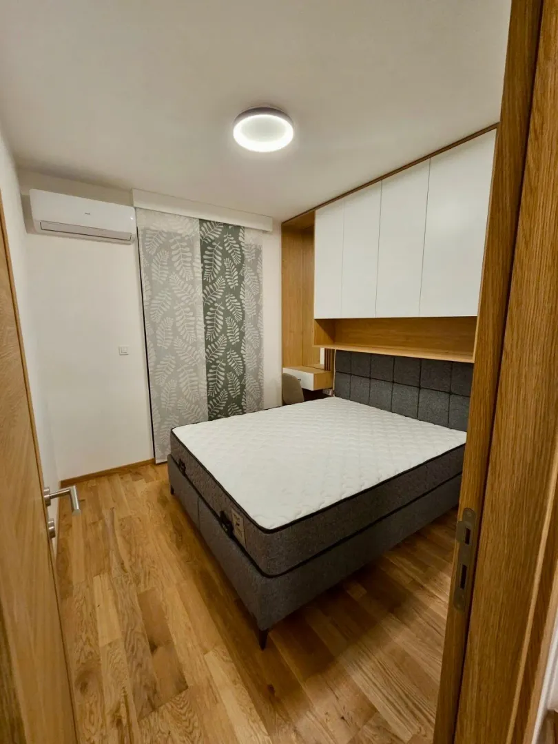Pogled na spavaću sobu sa bračnim krevetom i ugradnim plakarima.