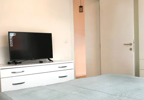 Spavaća soba sa krevetom, komodom i televizorom. - image 7