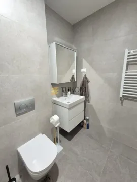 Modern bathroom tiled in grey with a wall-hung toilet and washbasin. - image 10