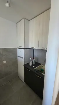 Small kitchen with a sink, refrigerator, and cabinetry. - image 6