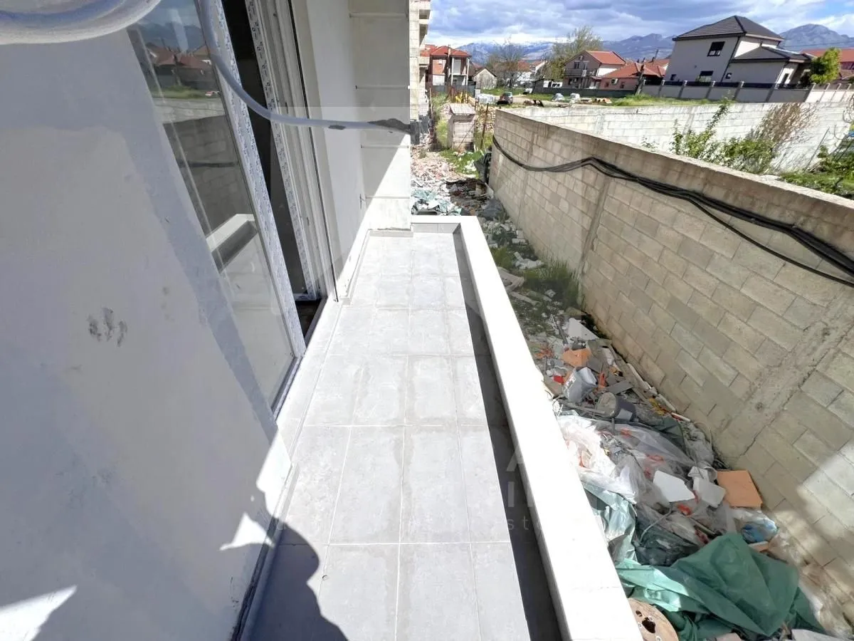 Nenamješten balkon sa popločanim podom i pogledom na okolinu.