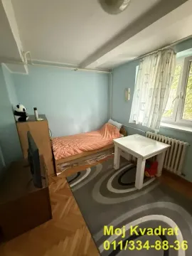 Manja spavaća soba sa krevetom, radnim stolom i televizorom. - image 11
