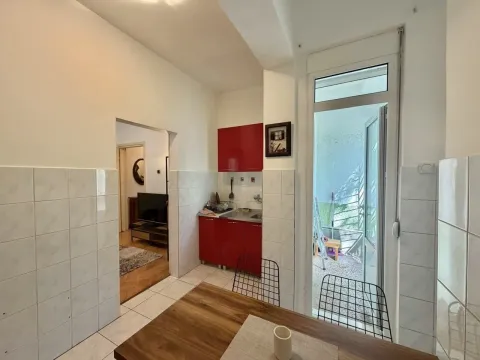 Kitchen with red cabinets and a dining table, with an exit to the terrace. - image 5