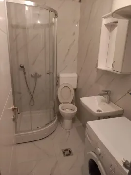 Bright bathroom featuring a shower cabin, sink, and washing machine. - image 11