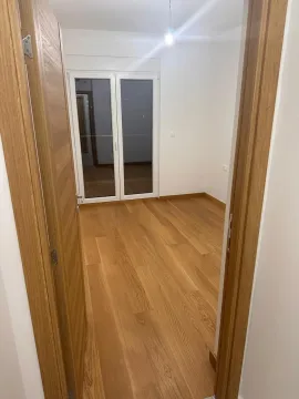 An empty room with white walls, wooden flooring, and balcony doors. - image 2