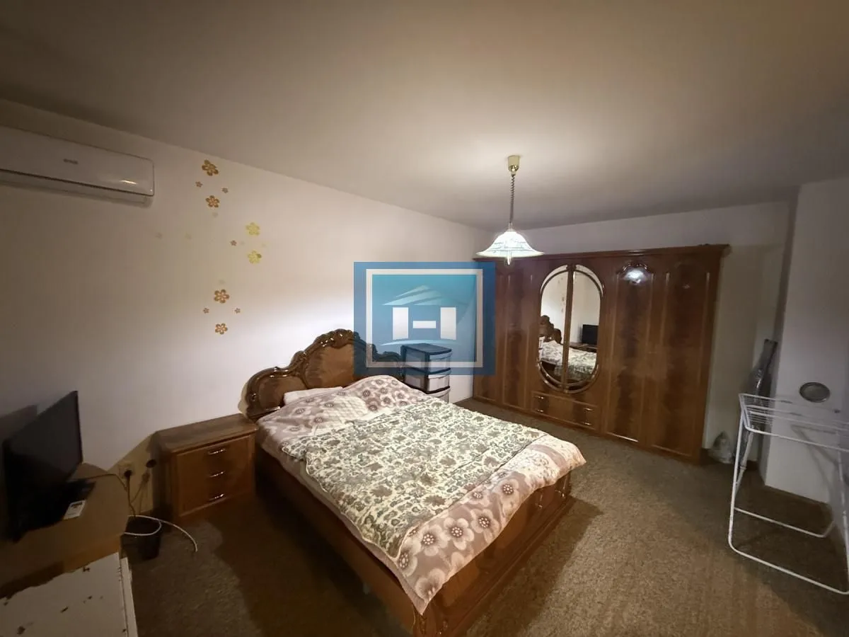 Furnished bedroom with a double bed and a wooden wardrobe.