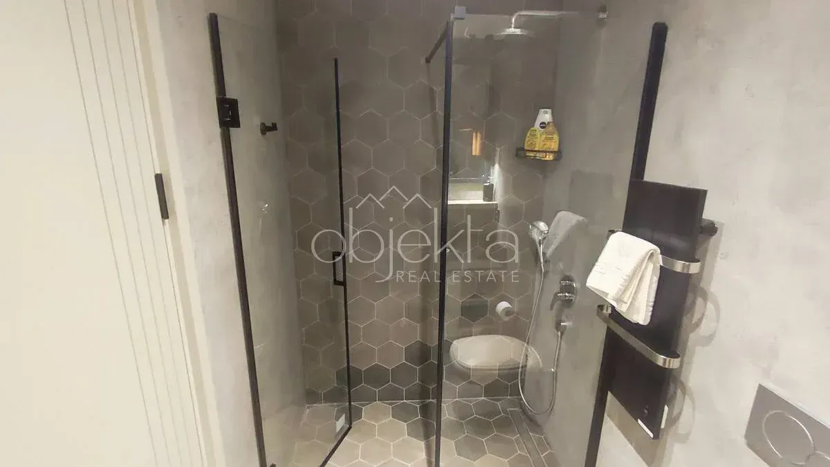 Moderno opremljeno kupatilo sa tuš kabinom i WC šoljom.