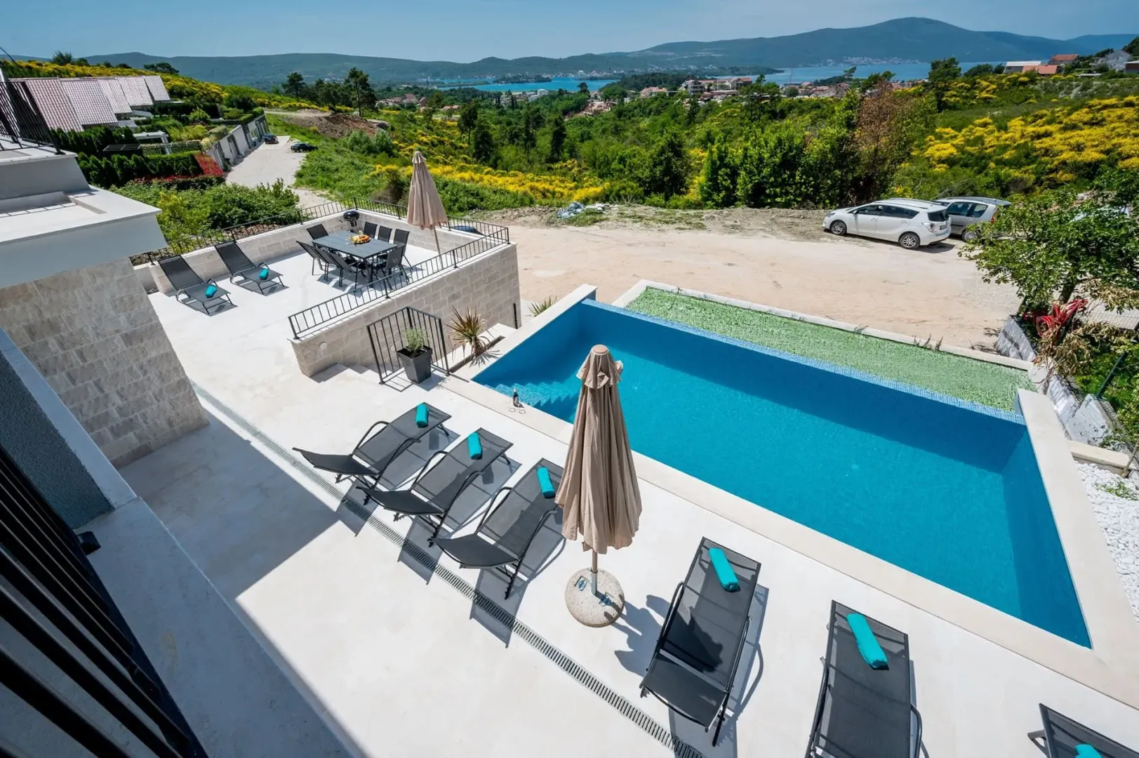 Terasa sa bazenom i ležaljkama ispred moderne vile sa pogledom na more.
