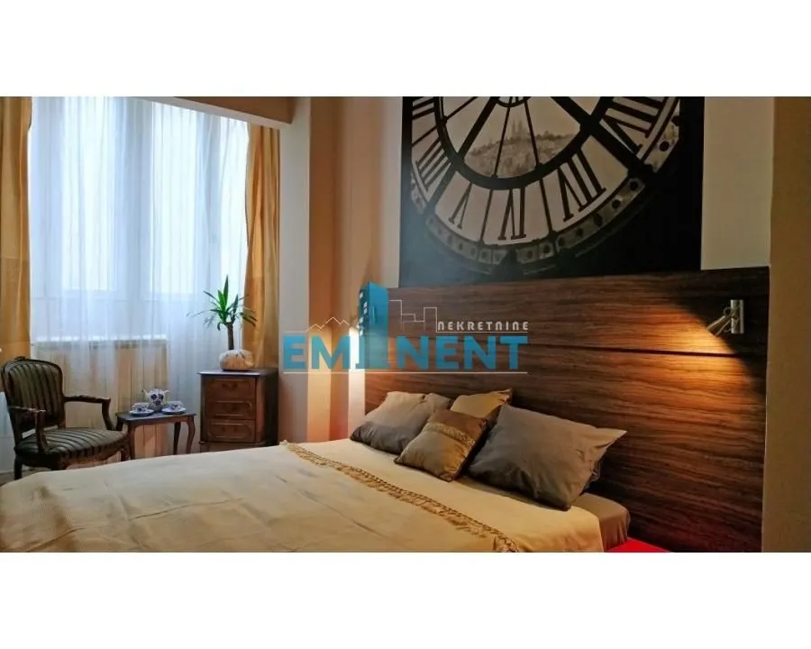 Bedroom with a double bed and a decorative wall with a clock motif.
