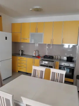 Bright kitchen with yellow cabinets and an adjacent dining table. - image 12