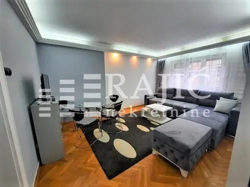 Living room with a sofa set, dining table, and parquet flooring.