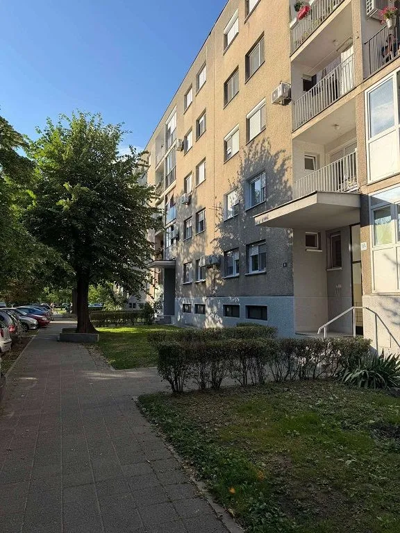 Spoljašnji izgled stambene zgrade sa prilazom i zelenom površinom.