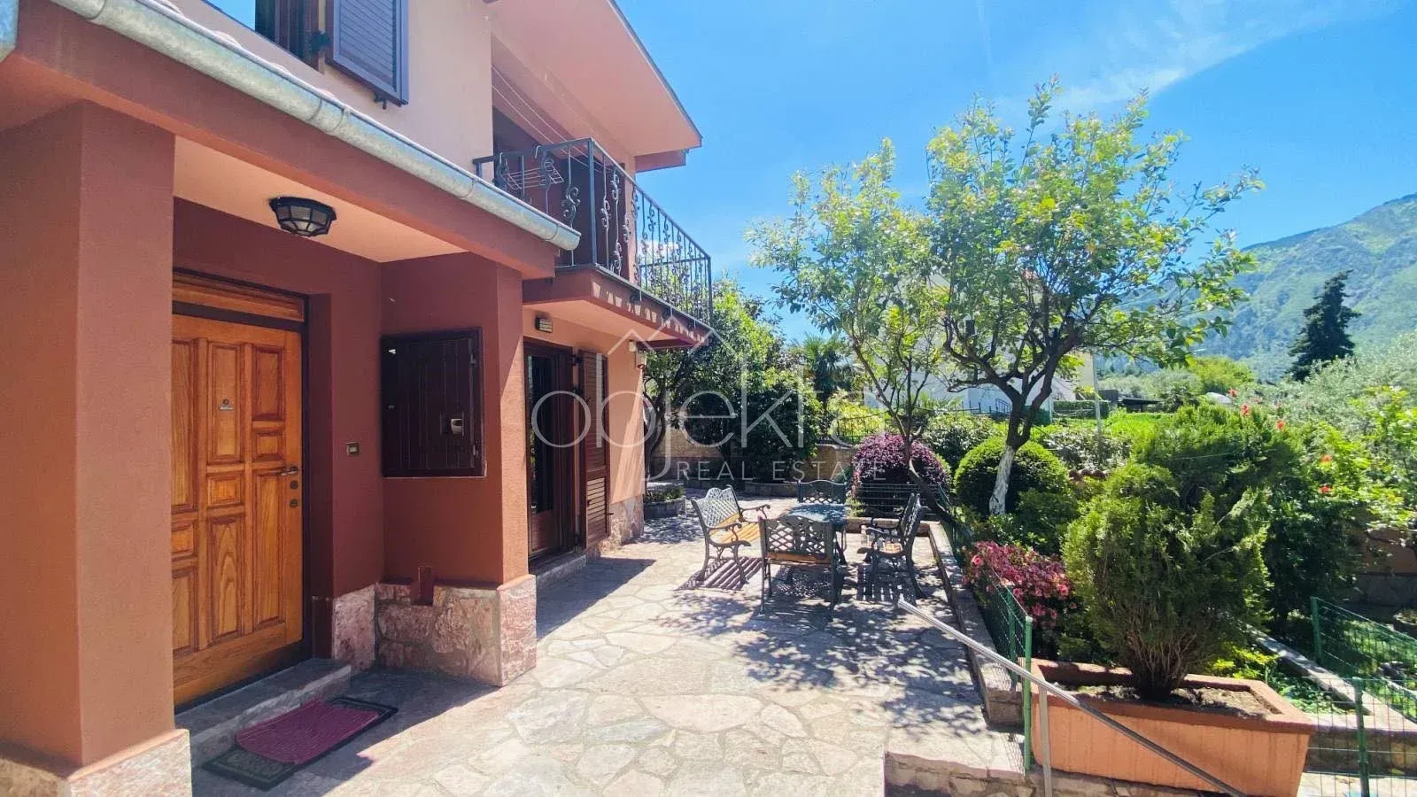 View of the house entrance and landscaped yard with seating furniture.