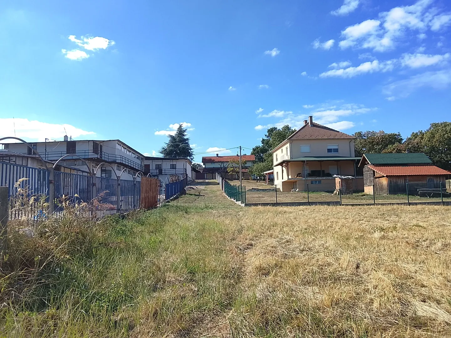 View of the yard and buildings with a lawn in the foreground.