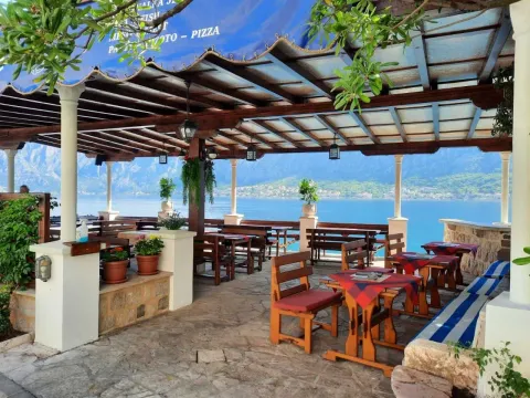 Natkrivena terasa restorana sa drvenim stolovima i pogledom na more. - image 11