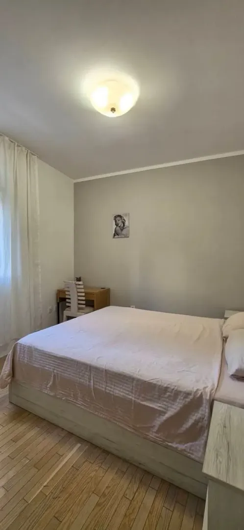 Namještena spavaća soba sa bračnim krevetom i radnim stolom.