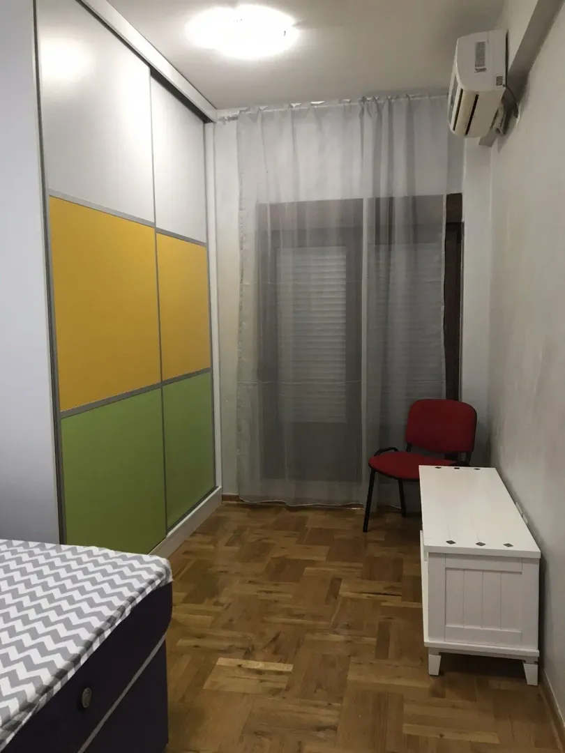 Bright bedroom featuring a large colorful wardrobe and parquet flooring.