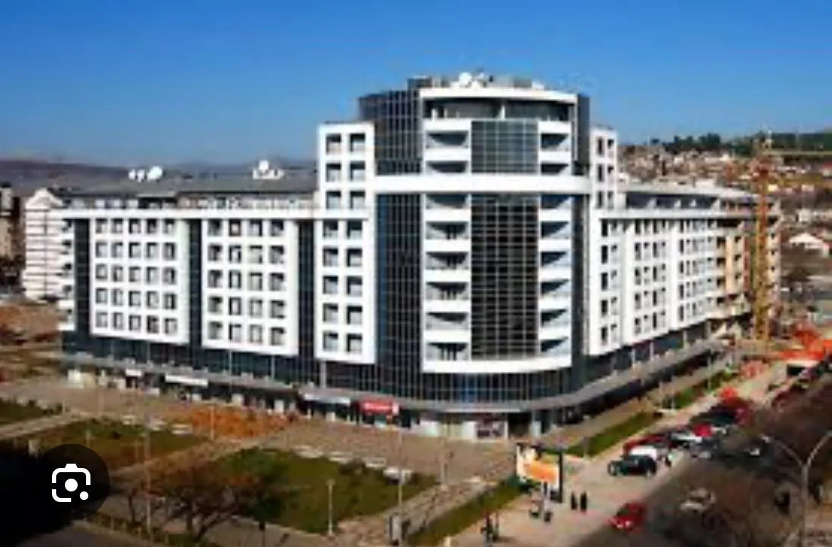 Pogled na spoljašnjost moderne višestambene zgrade sa velikim staklenim površinama i terasama.