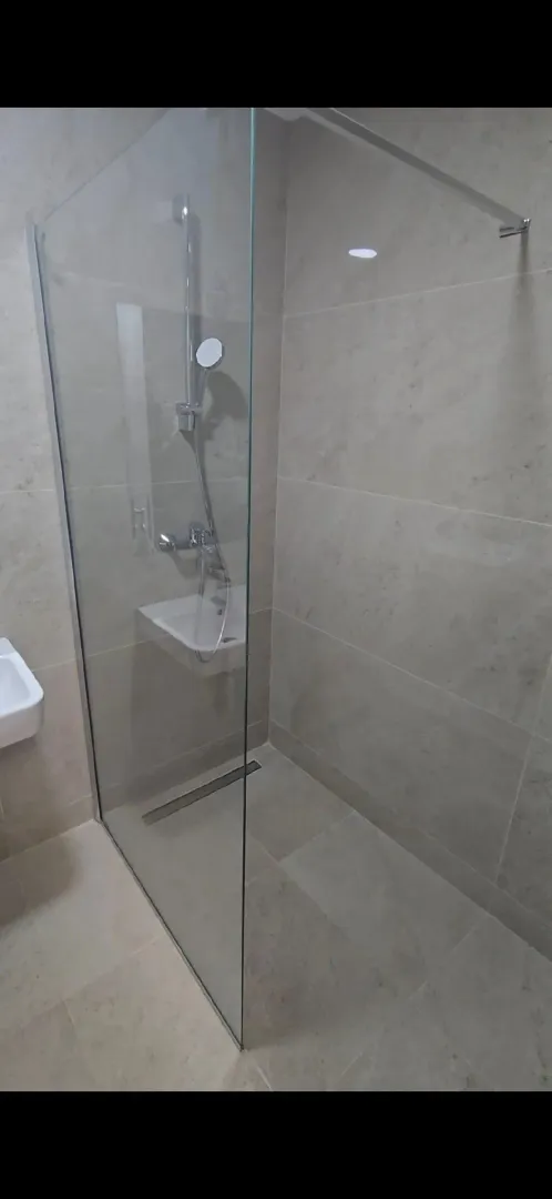 Moderne kupatilo sa tuš kabinom i keramičkim pločicama.