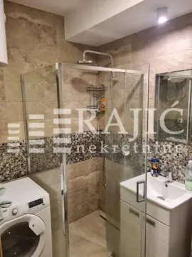 Small bathroom with a shower cabin, sink, and washing machine. - image 8
