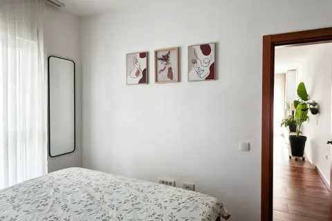 Svijetla spavaća soba sa krevetom i dekorativnim slikama na zidu. - image 11