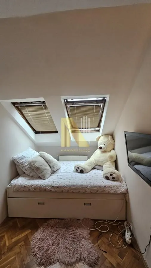 Manja spavaća soba sa krevetom ispod krovnih prozora.