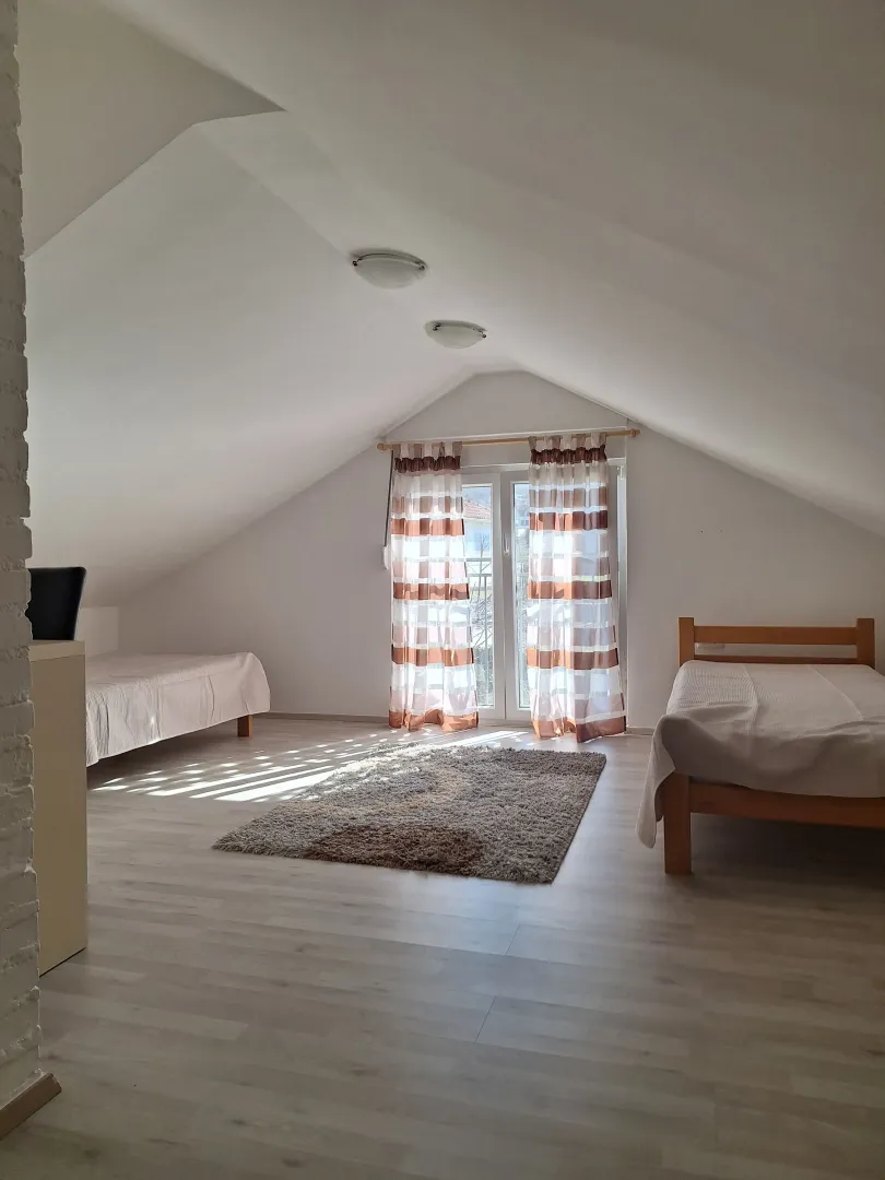 Potkrovlje opremljeno sa dva kreveta i izlazom na terasu.