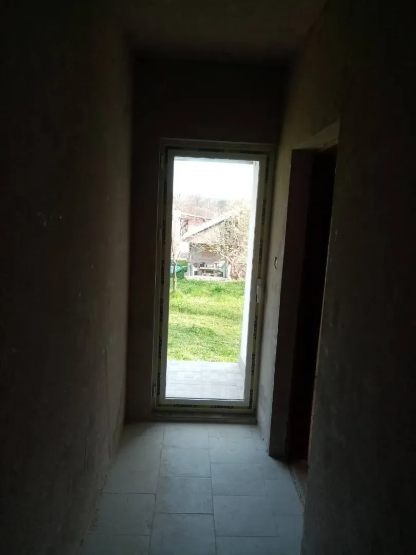 Unfinished hallway with a glass door leading to the yard.