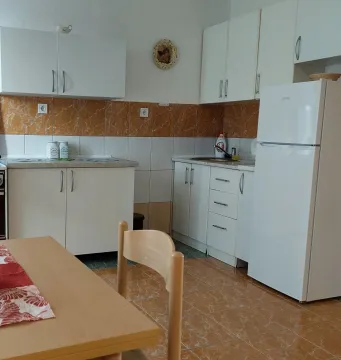 Small white kitchen with a dining table and refrigerator. - image 4