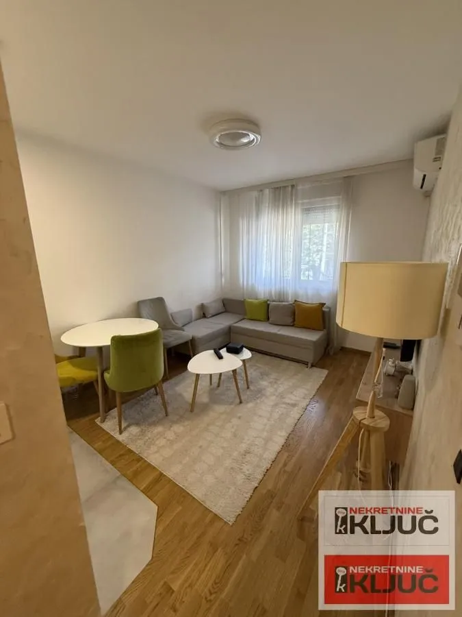 Dnevni boravak sa garniturom, trpezarijskim stolom i podnom lampom.